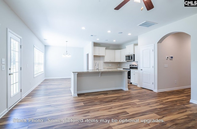 kitchen featuring white cabinets, an island with sink, appliances with stainless steel finishes, and dark wood-type flooring