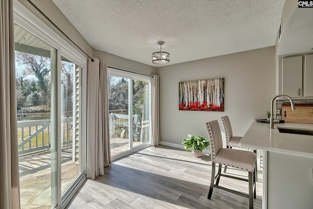 interior space featuring a chandelier, a textured ceiling, light hardwood / wood-style flooring, and sink