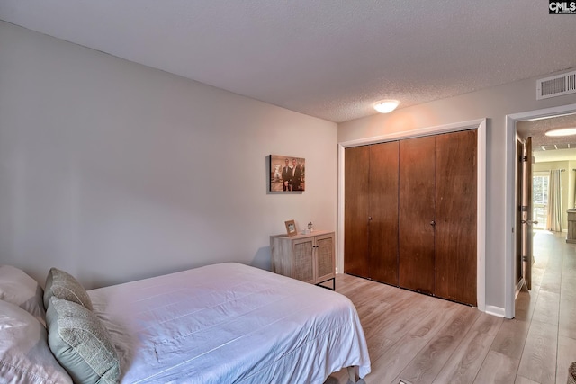 bedroom featuring light wood-type flooring, a textured ceiling, and a closet