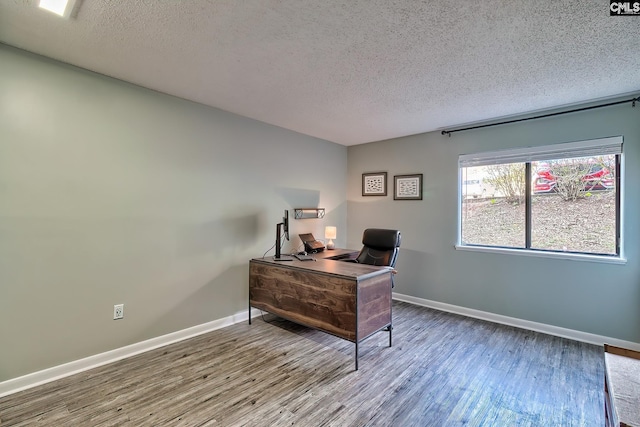 home office with a textured ceiling and hardwood / wood-style flooring