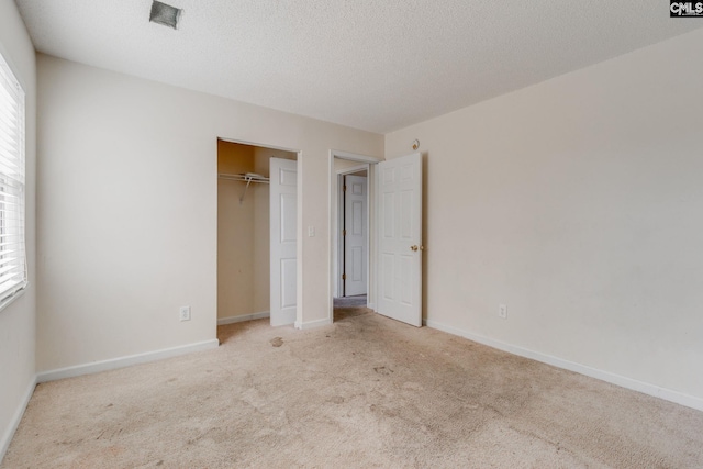 unfurnished bedroom with a closet, light colored carpet, and a textured ceiling