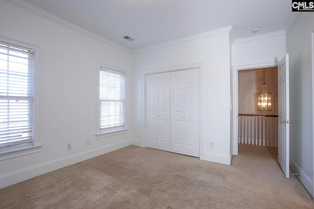 unfurnished bedroom featuring a notable chandelier, light colored carpet, ornamental molding, and a closet