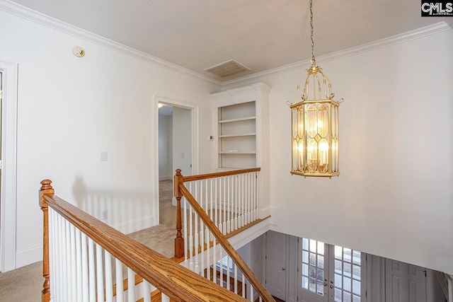 hall featuring light carpet, french doors, ornamental molding, built in shelves, and a notable chandelier