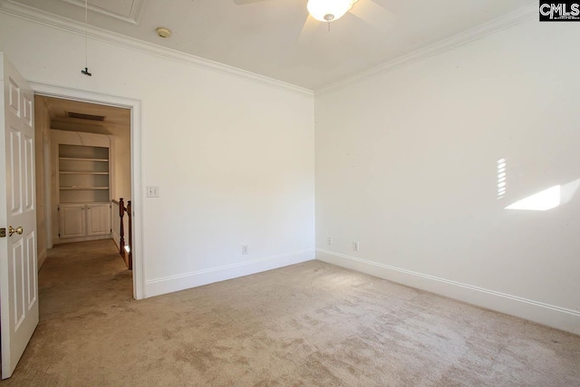 carpeted spare room featuring ceiling fan, crown molding, and built in shelves