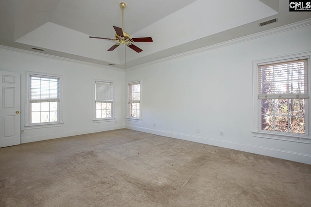 carpeted spare room with a tray ceiling, ceiling fan, plenty of natural light, and ornamental molding