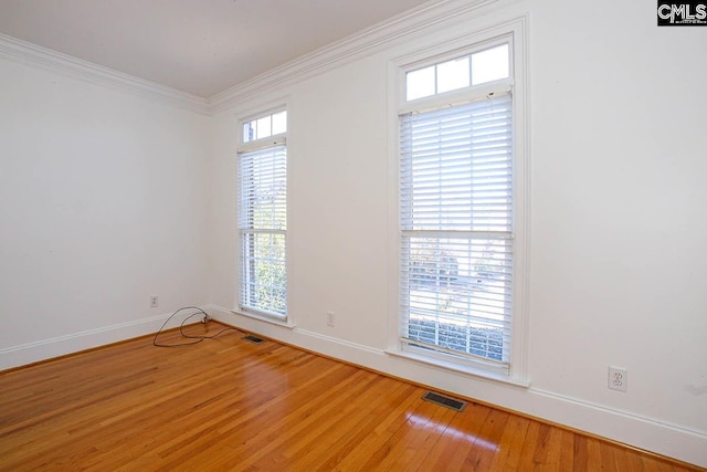 unfurnished room with hardwood / wood-style floors, a wealth of natural light, and ornamental molding