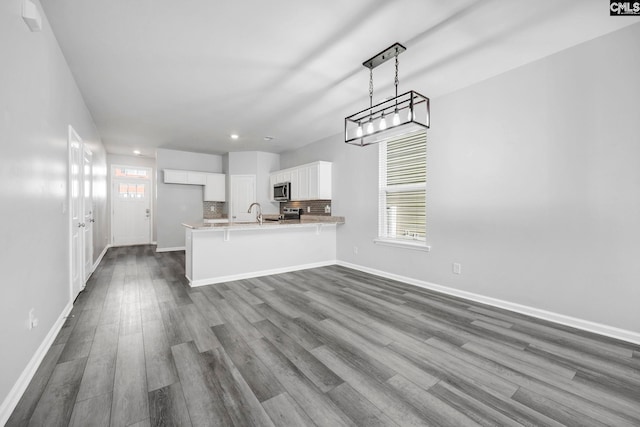 kitchen featuring a breakfast bar, white cabinetry, tasteful backsplash, decorative light fixtures, and kitchen peninsula