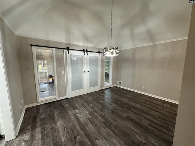 unfurnished dining area with vaulted ceiling, dark wood-type flooring, crown molding, a barn door, and a chandelier