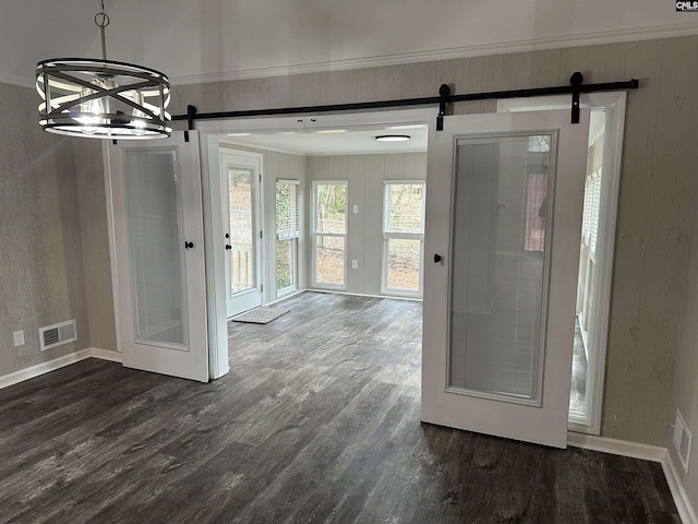 entrance foyer with a barn door, dark wood-type flooring, a notable chandelier, and ornamental molding