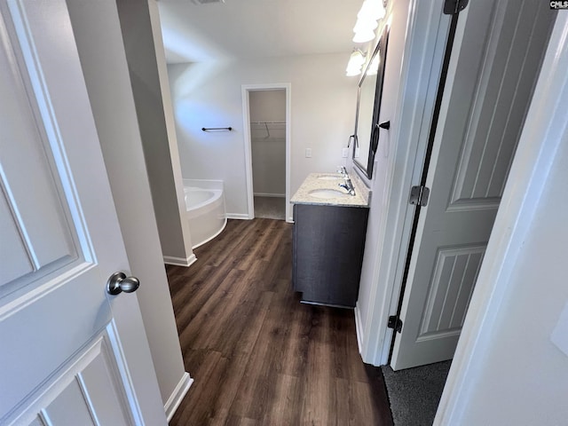 bathroom with a washtub, wood-type flooring, and vanity