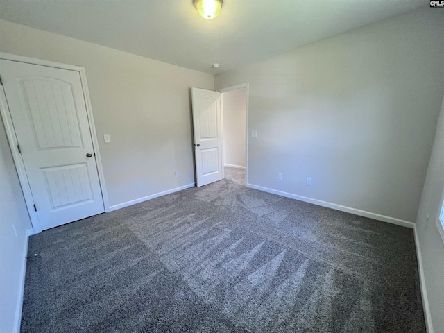 unfurnished room featuring dark carpet