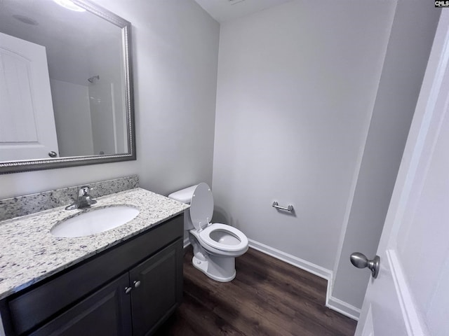 bathroom with walk in shower, hardwood / wood-style floors, vanity, and toilet