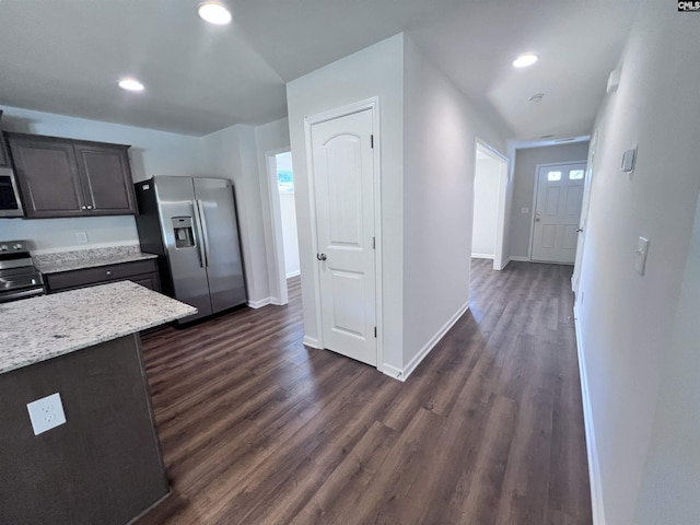 kitchen with dark hardwood / wood-style floors, light stone countertops, plenty of natural light, dark brown cabinetry, and stainless steel appliances