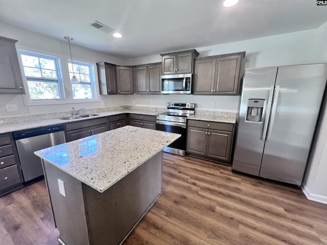 kitchen featuring stainless steel appliances, sink, a center island, dark hardwood / wood-style floors, and hanging light fixtures