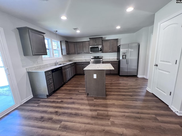 kitchen featuring dark wood-type flooring, sink, appliances with stainless steel finishes, decorative light fixtures, and a kitchen island