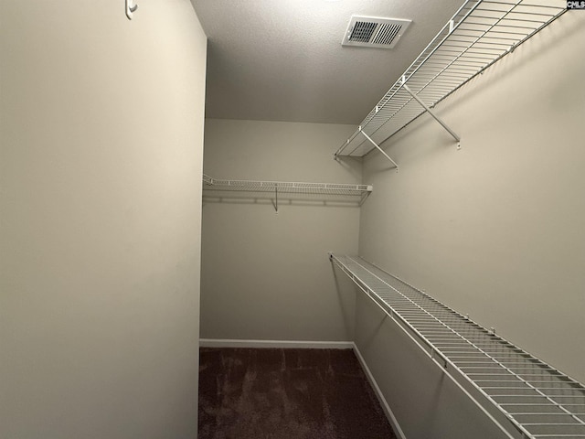 walk in closet featuring dark carpet