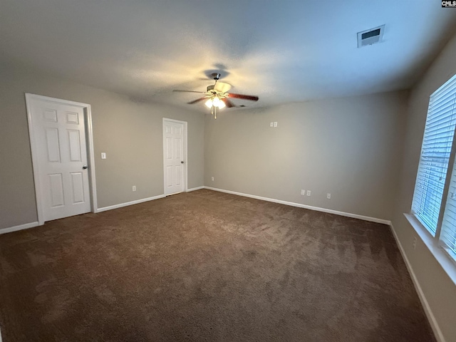 empty room with ceiling fan and dark carpet