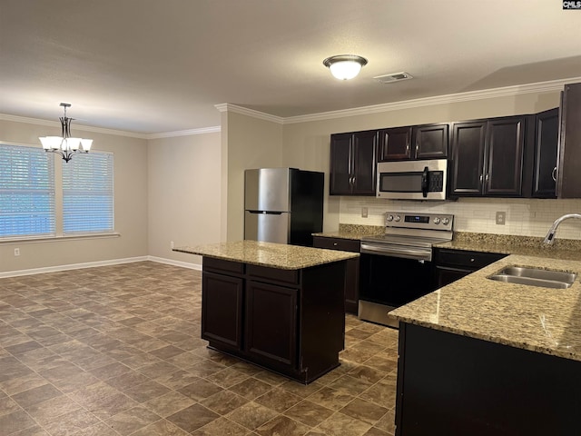 kitchen with an inviting chandelier, sink, decorative light fixtures, a kitchen island, and stainless steel appliances