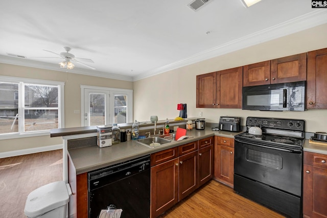 kitchen with black appliances, light wood-type flooring, and kitchen peninsula