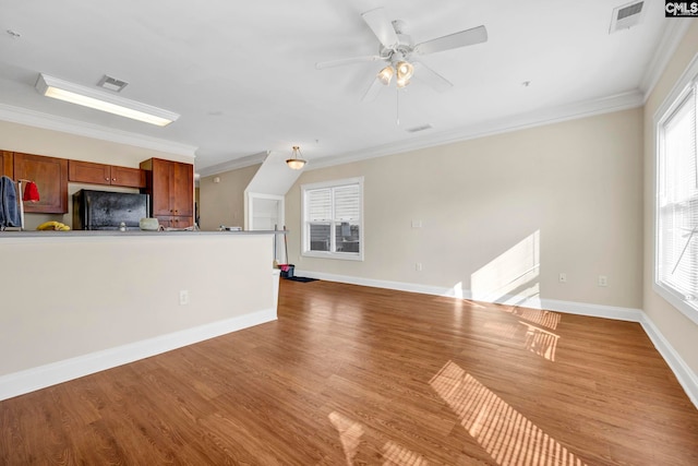 unfurnished living room featuring ceiling fan, a healthy amount of sunlight, light wood-type flooring, and ornamental molding