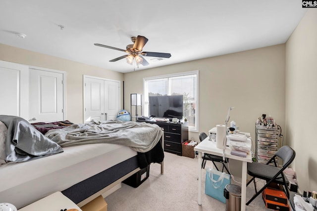 carpeted bedroom featuring ceiling fan and two closets