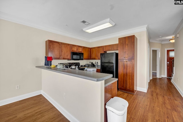 kitchen featuring black appliances, light wood-type flooring, kitchen peninsula, and crown molding