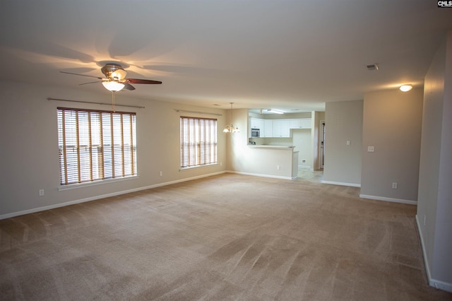 unfurnished living room with light colored carpet and ceiling fan with notable chandelier