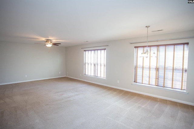 empty room with carpet floors and ceiling fan with notable chandelier