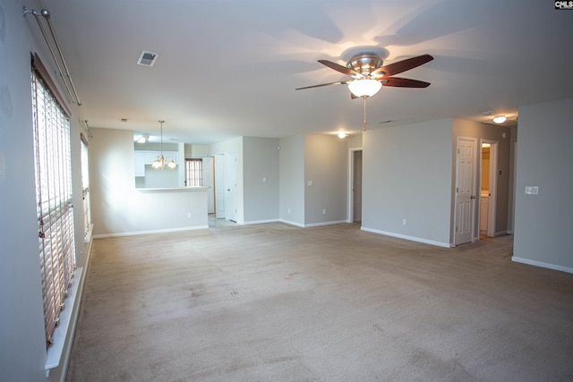 carpeted spare room with ceiling fan with notable chandelier