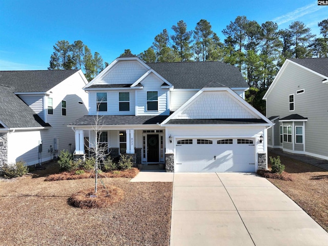 craftsman-style home with a porch, an attached garage, stone siding, driveway, and roof with shingles