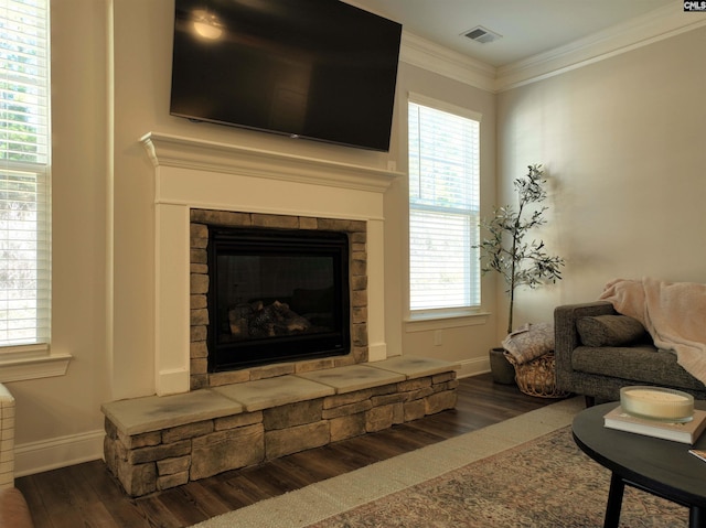 living room with a stone fireplace, dark hardwood / wood-style flooring, and ornamental molding