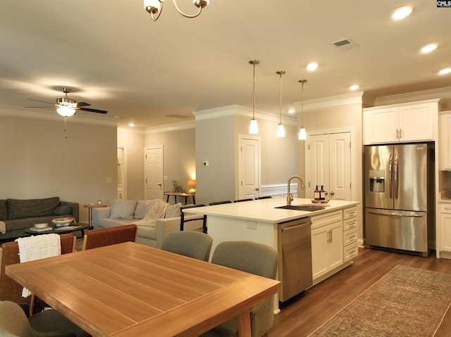 kitchen featuring dark wood finished floors, appliances with stainless steel finishes, white cabinetry, a sink, and an island with sink