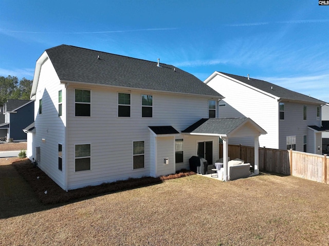 back of house with a shingled roof, fence, and a patio