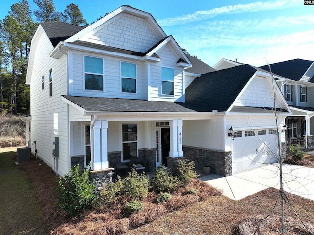 craftsman inspired home featuring central AC unit, a porch, and a garage