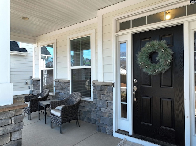 doorway to property with stone siding and a porch