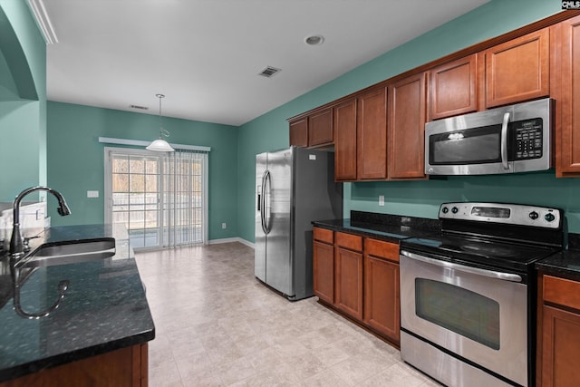 kitchen with hanging light fixtures, sink, appliances with stainless steel finishes, and dark stone counters