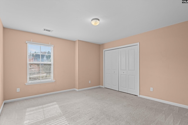 unfurnished bedroom featuring light carpet and a closet