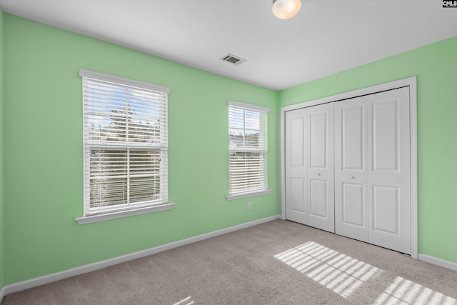 unfurnished bedroom with light carpet and a closet