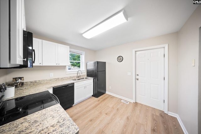 kitchen with black appliances, sink, light hardwood / wood-style floors, light stone counters, and white cabinetry