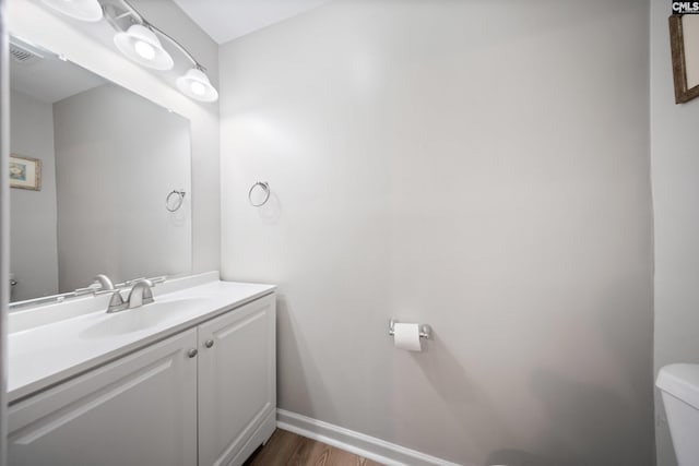 bathroom with hardwood / wood-style floors, vanity, and toilet