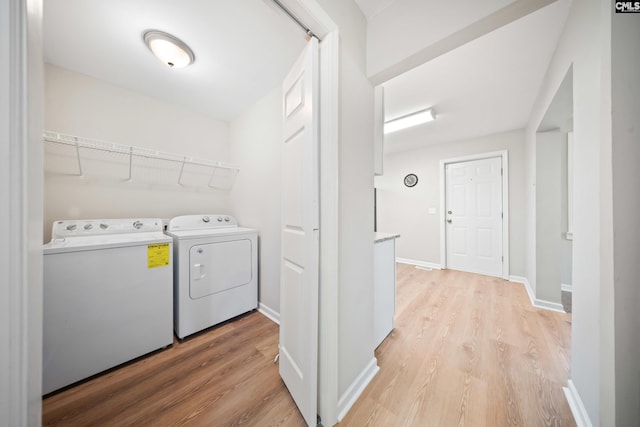 laundry room with washing machine and clothes dryer and light hardwood / wood-style floors