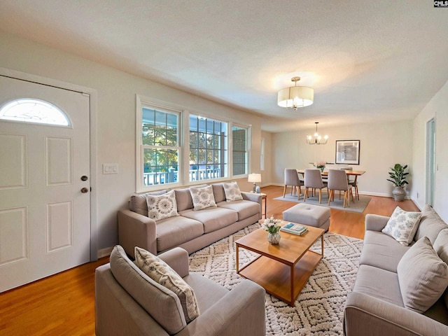 living room featuring light wood-type flooring, a textured ceiling, and a chandelier