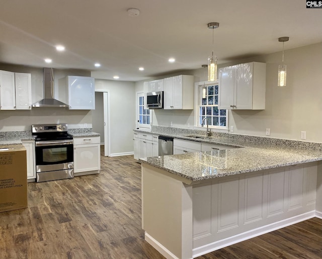 kitchen featuring kitchen peninsula, appliances with stainless steel finishes, white cabinetry, and wall chimney exhaust hood