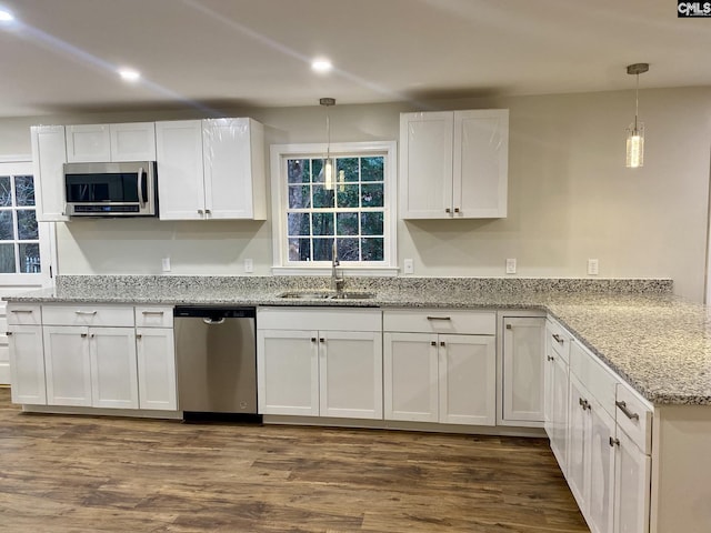 kitchen with hanging light fixtures, white cabinetry, sink, and stainless steel appliances