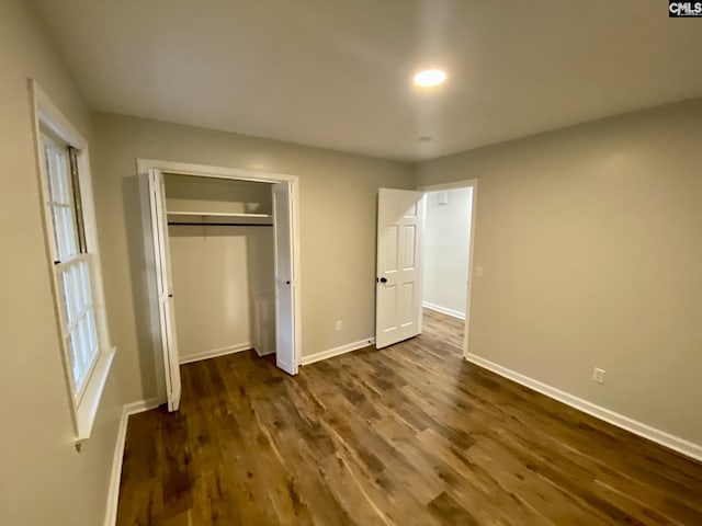 unfurnished bedroom featuring a closet and dark wood-type flooring