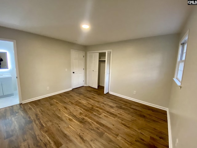 unfurnished bedroom featuring ensuite bathroom and dark wood-type flooring