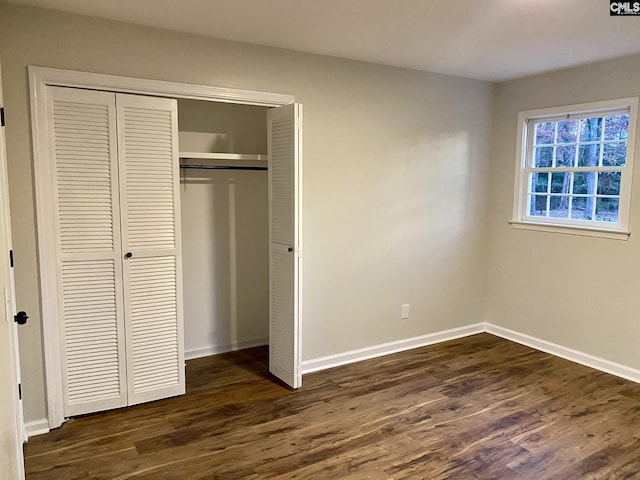 unfurnished bedroom featuring a closet and dark wood-type flooring