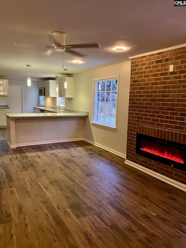 unfurnished living room with dark hardwood / wood-style floors, ceiling fan, sink, and a fireplace