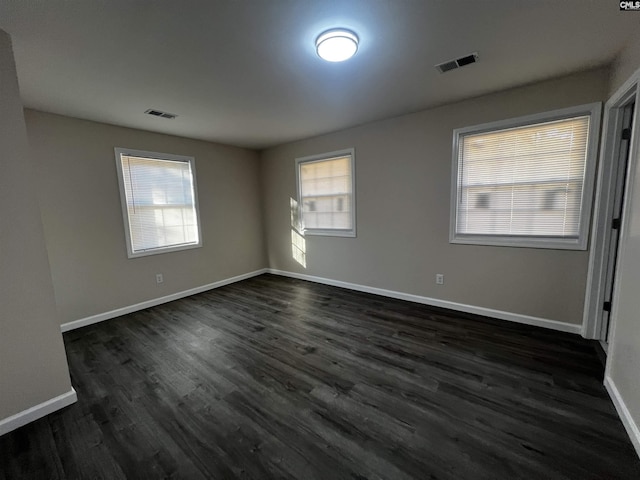 spare room featuring dark hardwood / wood-style flooring and plenty of natural light