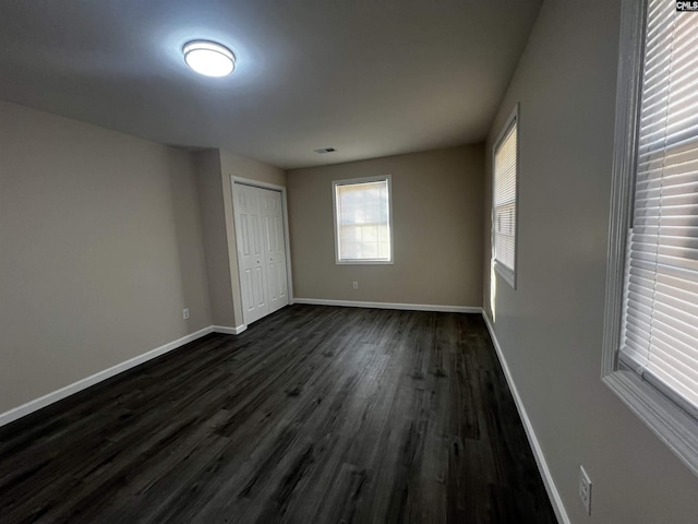 unfurnished bedroom featuring dark wood-type flooring and a closet